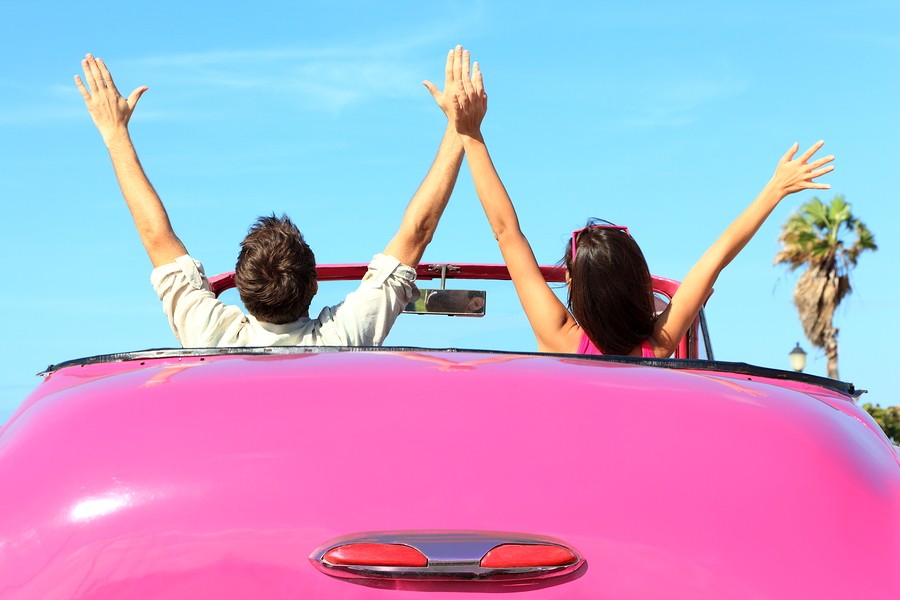 Freedom - happy free couple in car driving in pink vintage retro car cheering joyful with arms raise
